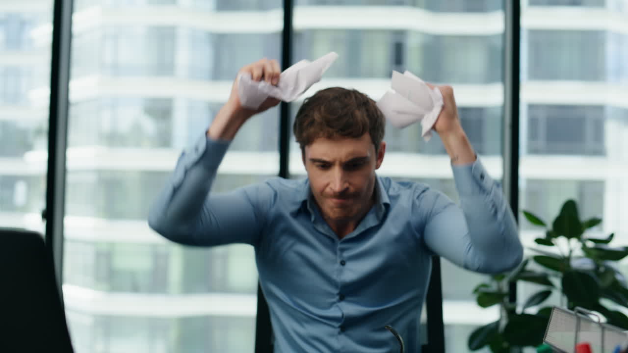 화가 난 사업가가 스트레스를 느끼고 사무실에서 종이를 던지고 있습니다.