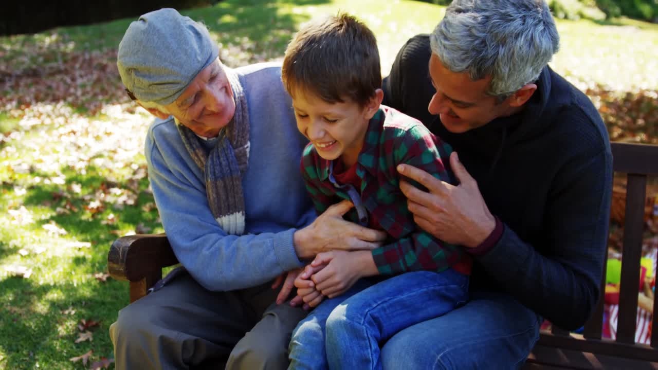 grandfather father and son laughing outdoors