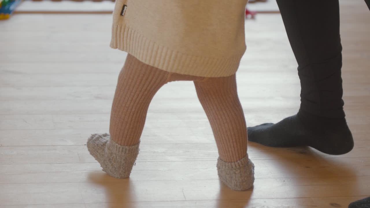 Baby macht erste Schritte auf Holzboden. Herzerwärmender Moment, perfekt für Familien- und Erziehungsprojekte.