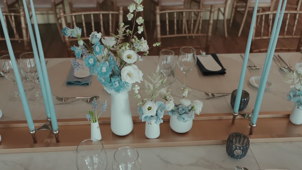 Pengaturan meja pernikahan mewah dengan centerpiece bunga biru dan lilin