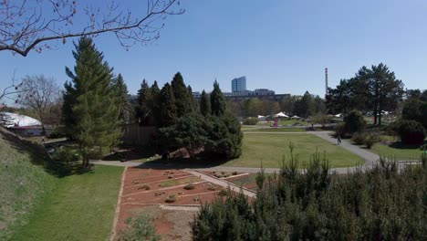 Botanical-garden-in-Olomouc,-diverse-species-of-plants-sprouting-on-a-sunny-spring-day,-city-skyline-in-the-background,-Czech-Republic