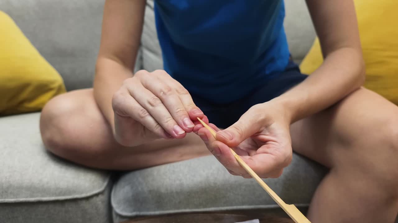 Hands working with a wooden chopstick on a couch