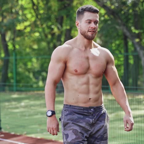 muscular runner on the outdoor stadium. portrait of a strong athlete without shirt prepares for running on a track. slow motion.