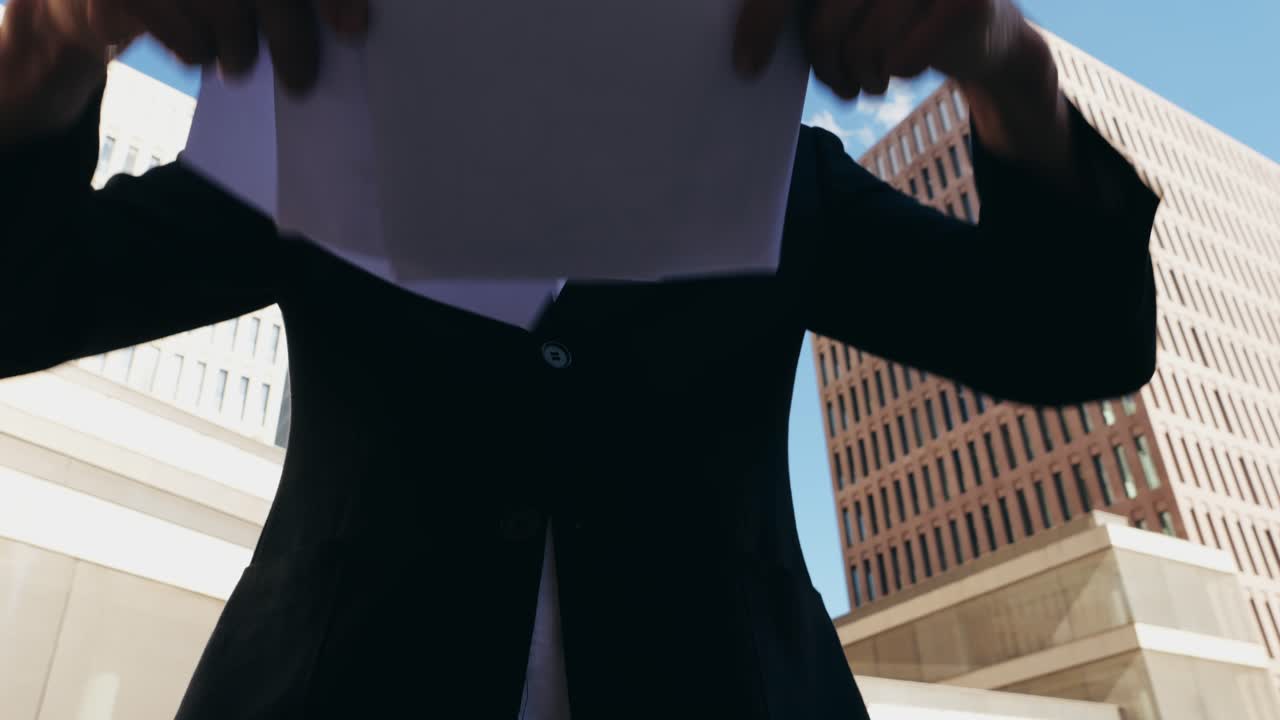 Business professional reviewing documents in front of an office building