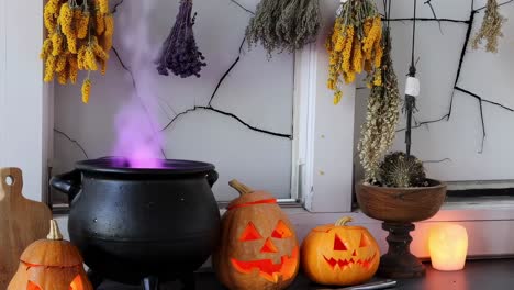 halloween still life with cauldron emitting purple smoke, carved pumpkins, dried flowers and candle