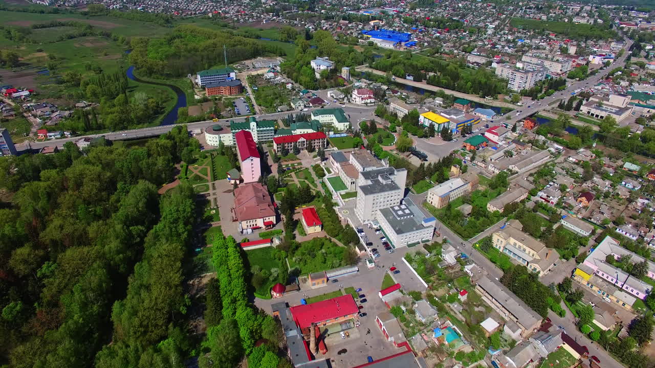 Flight over the residential districts with blocks of flats and cottages, roads and green areas. Aerial perspective on summer day.