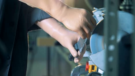 cerca de las manos protésicas afilando un cuchillo con un mecanismo de torneado