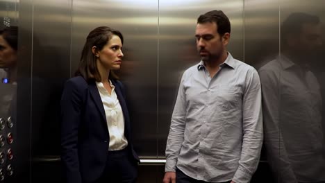 two individuals stand silently in a crowded elevator, their expressions revealing discomfort. the atmosphere is thick with tension as they avoid eye contact.