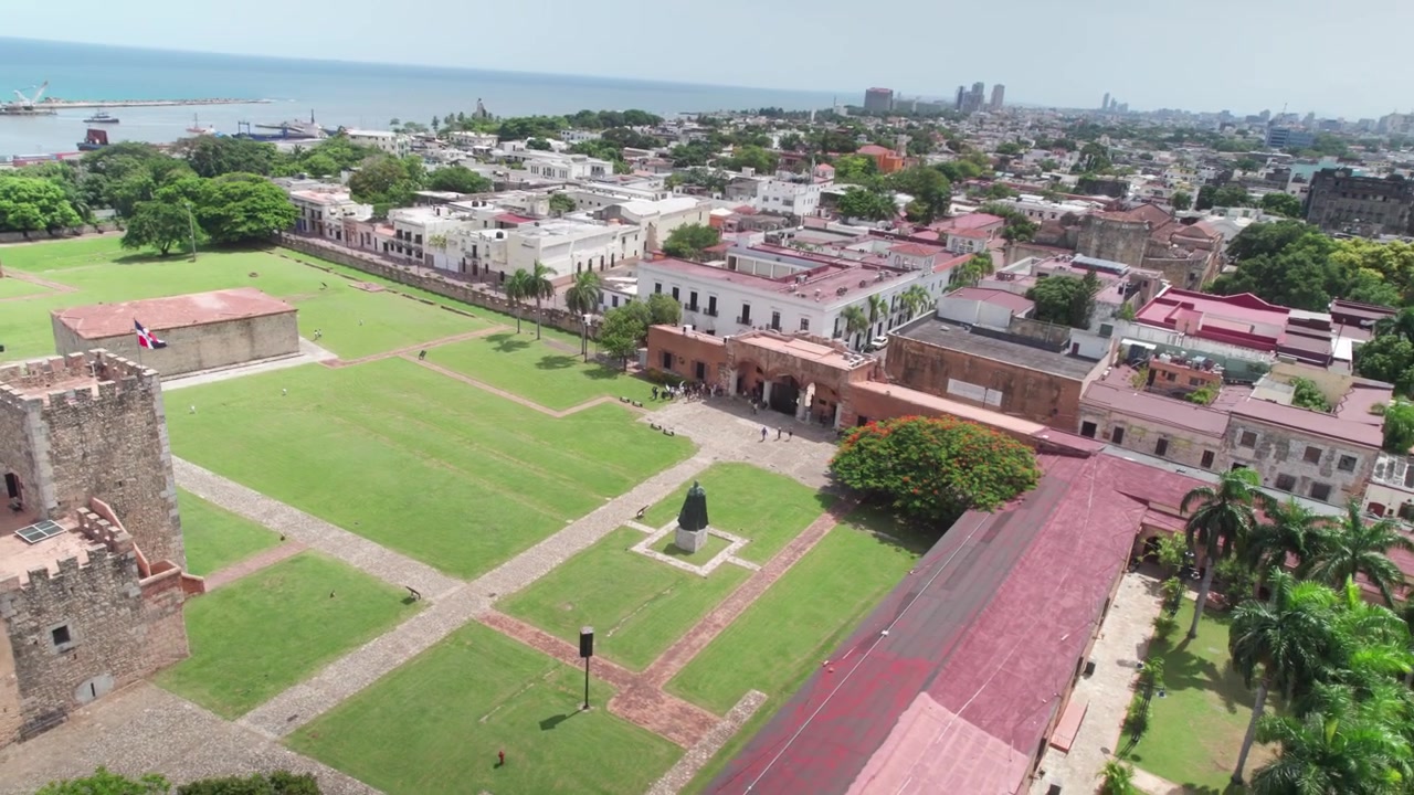 Vista aerea con drone della storica Fortezza Ozama, degli edifici coloniali e del fiume Ozama a Santo Domingo, che evidenzia il paesaggio urbano e l'infrastruttura portuale.