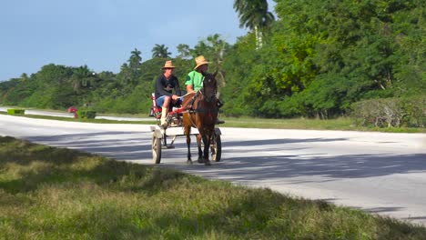 horse carts move along a highway in cuba