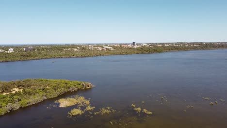 un lago azul profundo con follaje verde por debajo y cielo azul por encima, aéreo