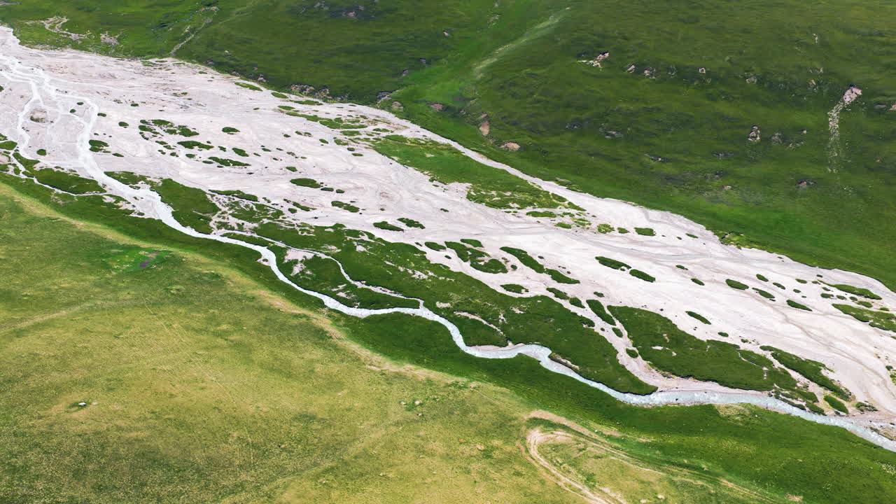 Fiume intrecciato Sary Jaz che scorre attraverso un verde prato alpino a Issyk-Kul, Kirghizistan. Ripresa aerea.