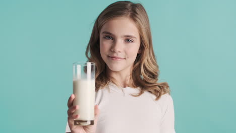 teenage caucasian girl in pijamas holding a glass of milk and nodding.