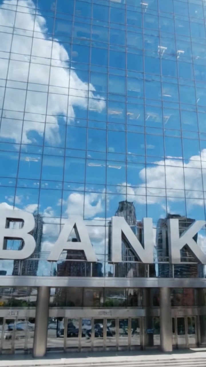 Un Edificio Bancario Moderno que Refleja la Vida Urbana con una Impresionante Fachada de Cristal Iluminada por un Cielo Brillante y Reflejando el Horizonte a la Vista