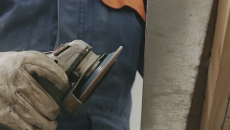 industrial close-up of worker grinding metal piece detail in protective gloves