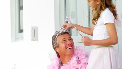 hija en disfraz de ángel poniendo una corona en la cabeza de su padre 4k