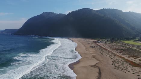 aerial view of playa grande showing waves crashing on the coastline in quintay, chile. push forward shot