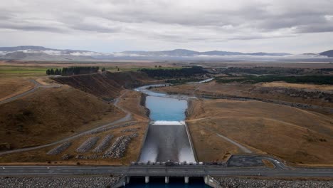 blue glacial water spilling through dam into beautiful river