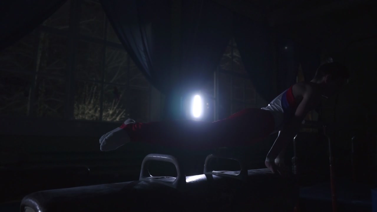 Male Gymnast performs exercises from the Olympic program on Pommel horse performing spins and rolls in slow motion