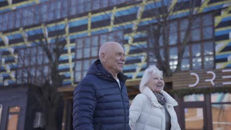 side view of a senior couple holding hands and walking down the street on a winter day