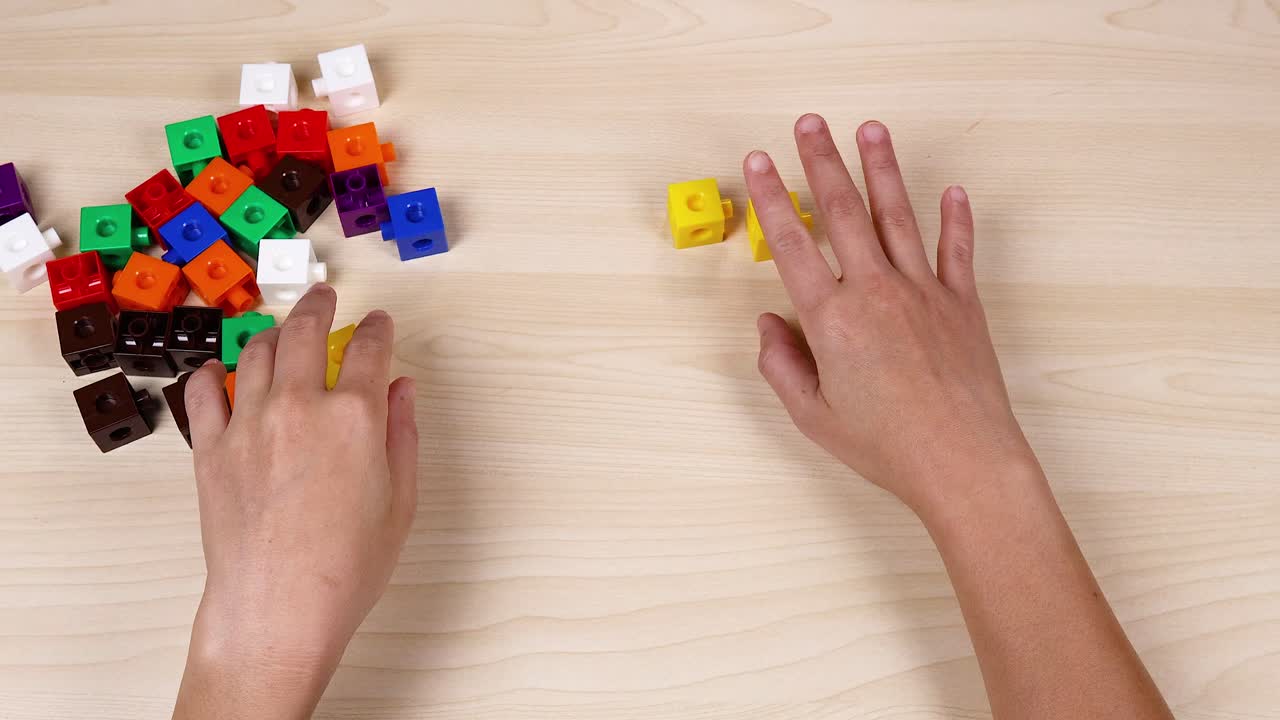 Hands organizing colorful cubes on a table