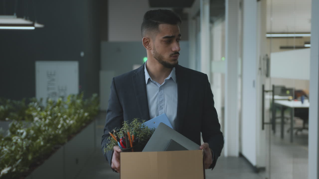 Man leaving office with personal belongings after job loss