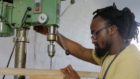 carpenter drilling wooden plank with machine in workshop 4k