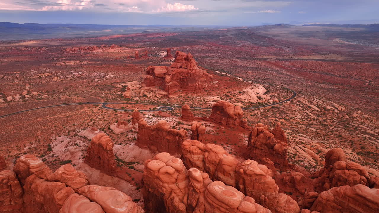 Boblende klipper i en gruppe midt i den store ørken. Bølgende motorvej gennem Arches National Park, USA. Luftfoto