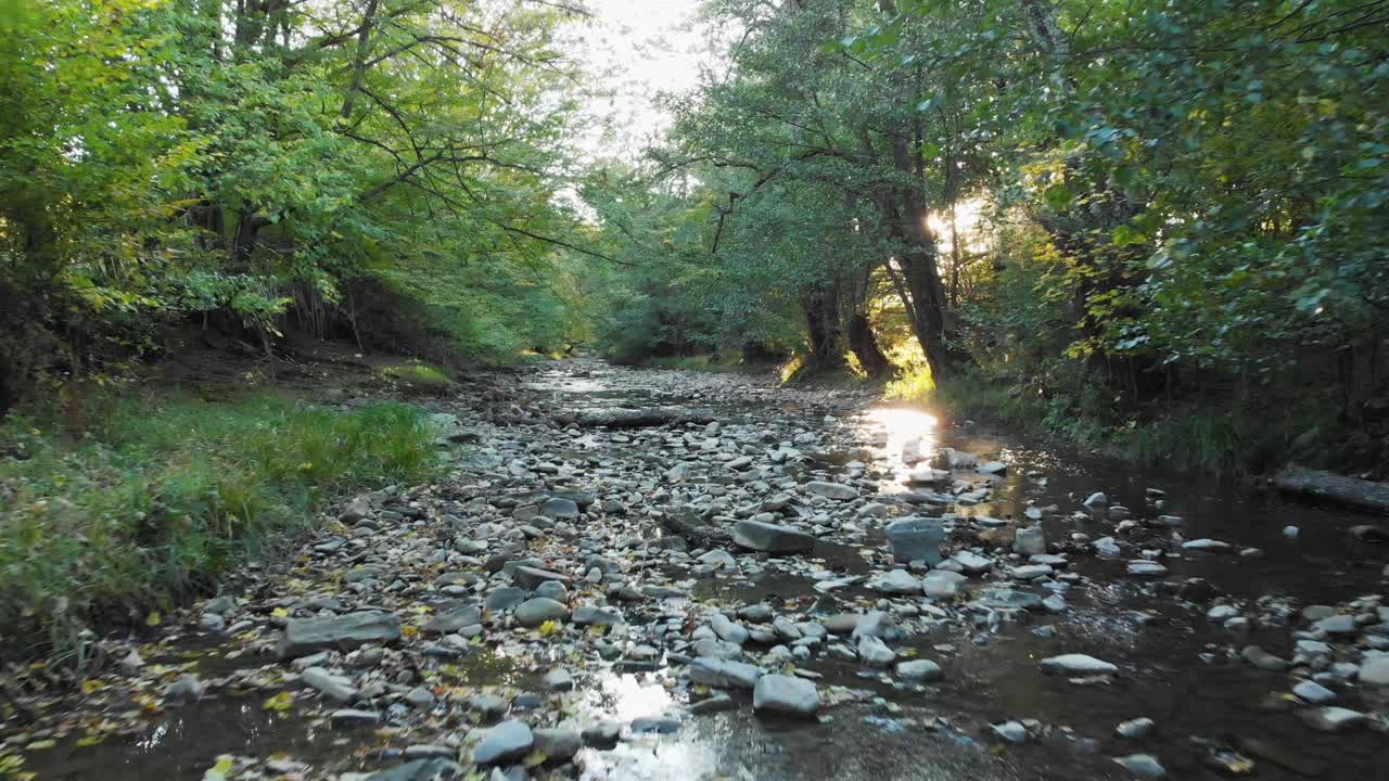 일몰-1에서 작은 강을 가로지르는 낮은 드론 비행