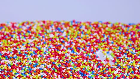 a dense layer of colorful sprinkles spreads evenly across a flat surface, creating a lively and textured pattern.