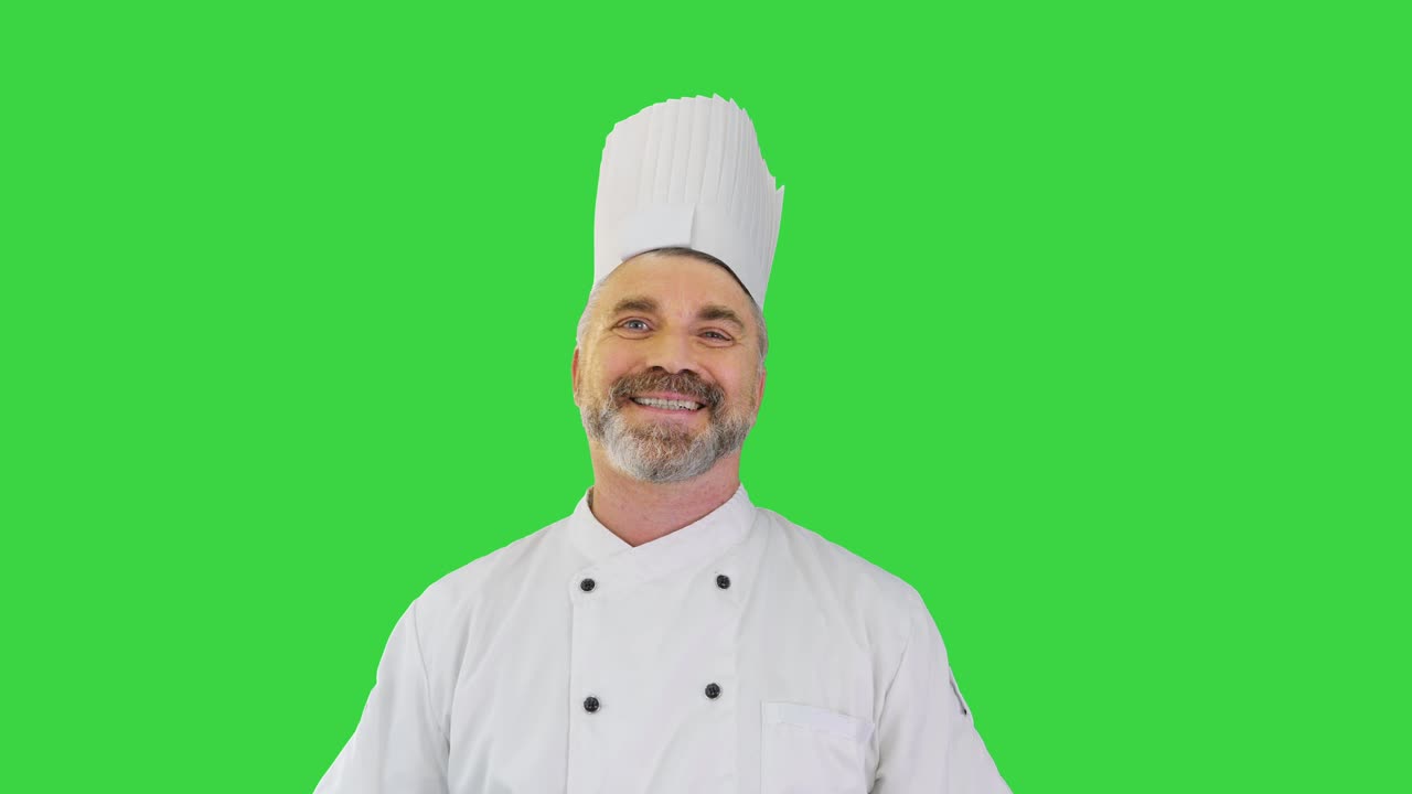 Cuoco che si toglie la mascherina medica e sorride alla telecamera su uno schermo verde, Chroma Key.