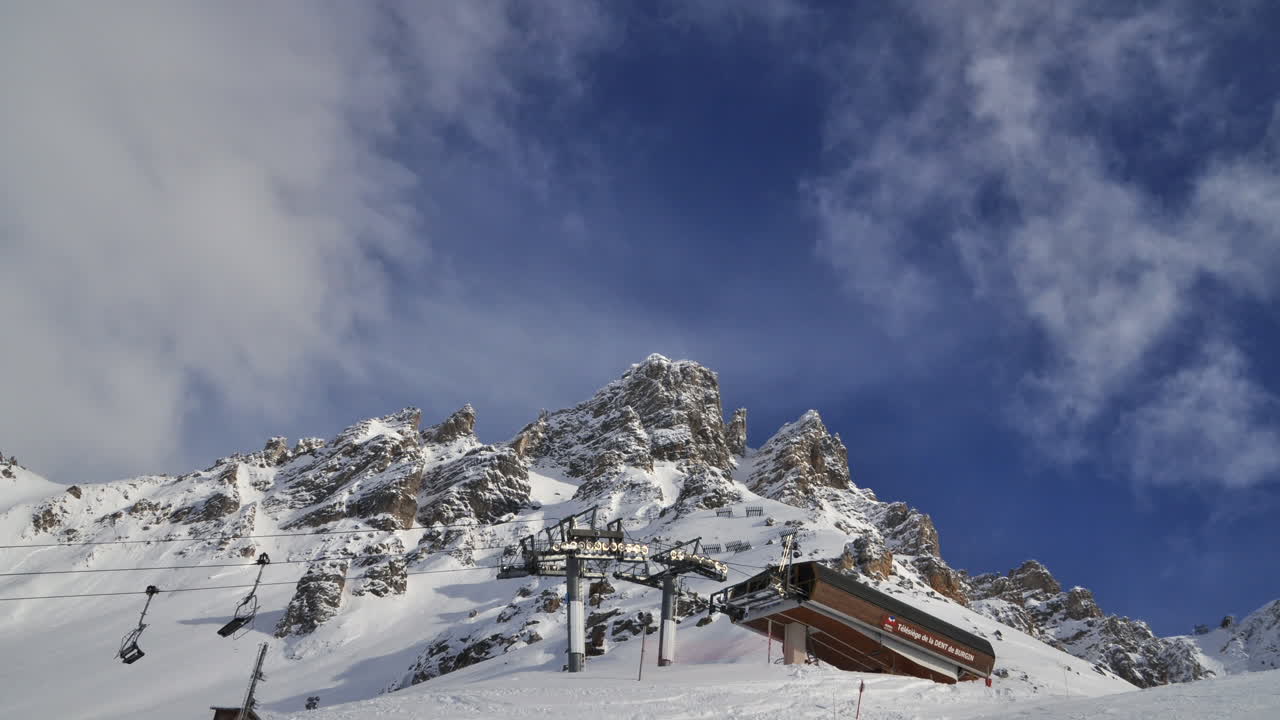 lapso de tiempo de un telesilla de esquí en meribel en los alpes franceses, con un pico de montaña y una nube en movimiento