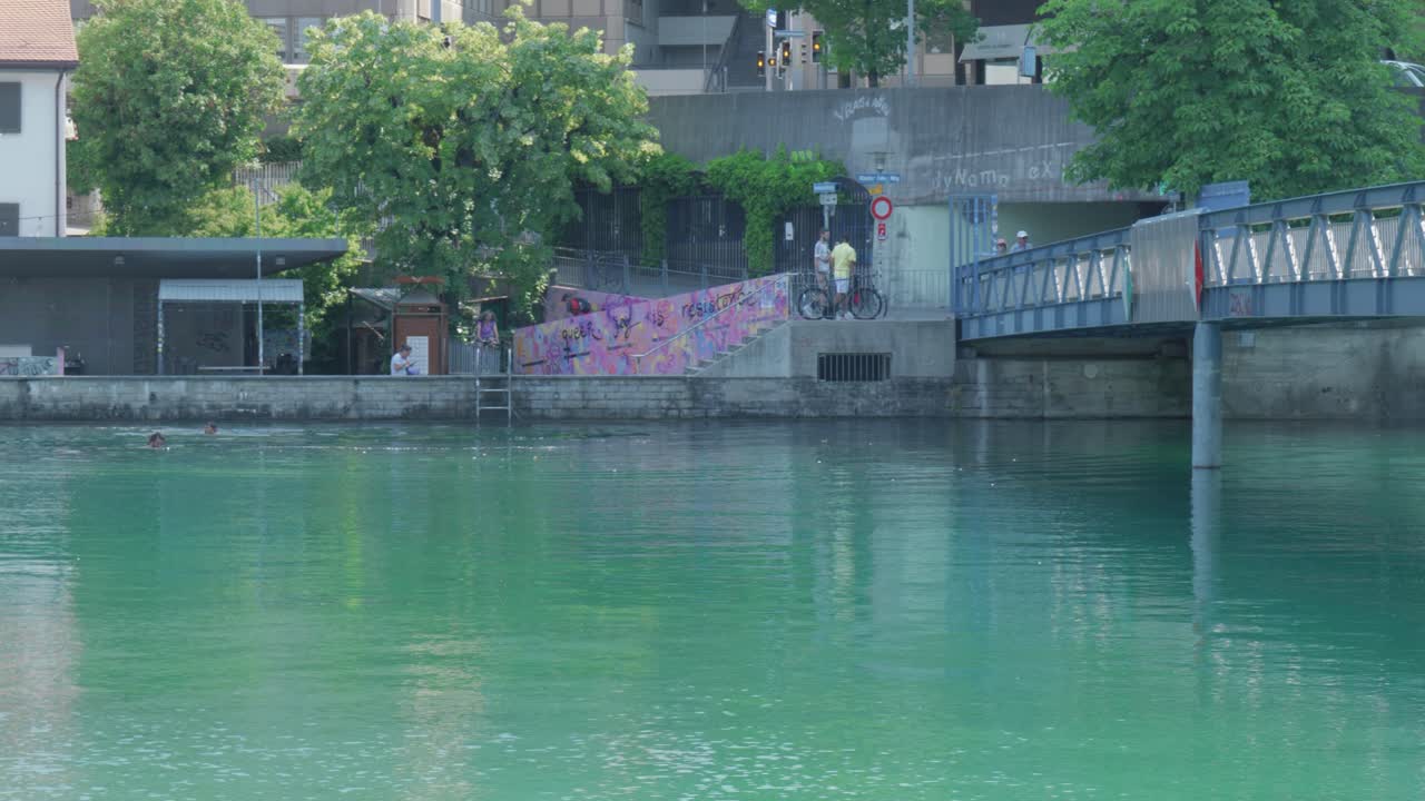 스위스 취리히의 운하를 가로지르는 보행자 다리의 수면에서 찍은 판으로 계단에 그래피티가 있습니다.