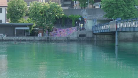 Pan-Shot-from-Water-Level-of-Pedestrian-Bridge-over-Canal-in-Zurich-with-Graffiti-on-Stairs