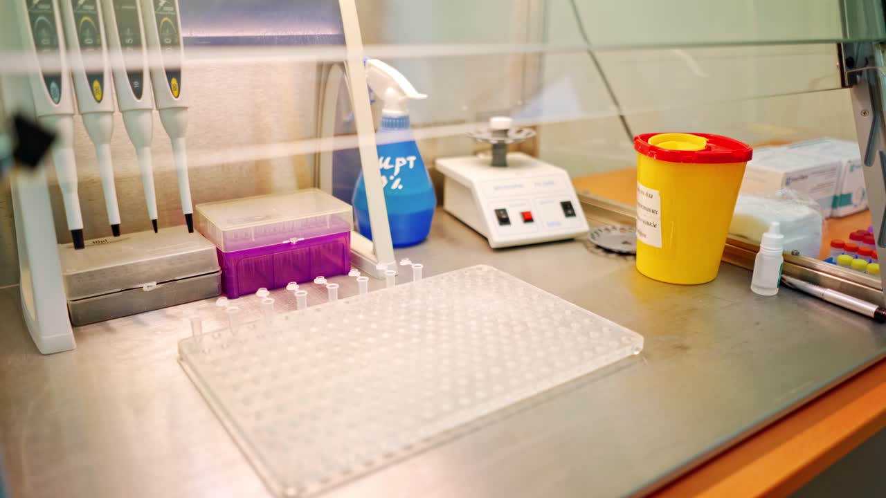 Hand of laboratory worker with tweezers on the table. Assistant putting empty sterile vials into the rack with tweezers in research clinic.