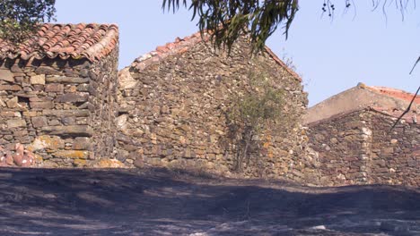 The-blackened,-still-smoking-ground-next-to-the-mountain-houses-after-a-forest-fire