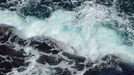 HD-Hawaii-Kauai-slow-motion-static-looking-down-at-ocean-waves-crashing-and-swirling-on-rocks-in-lower-left-frame