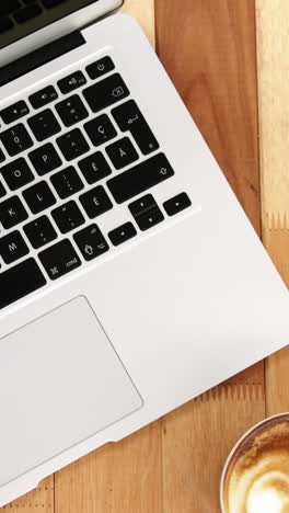 primer plano de una computadora portátil con taza de café y bloc de notas