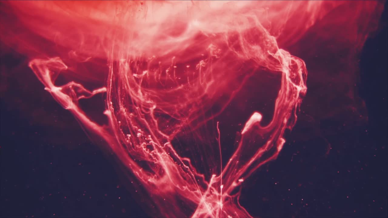 Encre rouge vibrante tourbillonnant et se propageant dans l'eau sombre