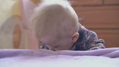 active boy in warm shirt tries to climb up on large soft bed