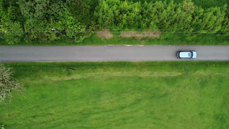 driving-through-mountains-in-modern-SUV-car,-aerial-video,-drone,-driving-in-foggy-green-mountains,-SUV