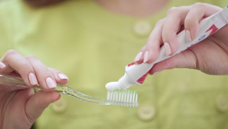 close up woman hands squeezing toothpaste on toothbrush. oral hygiene concept