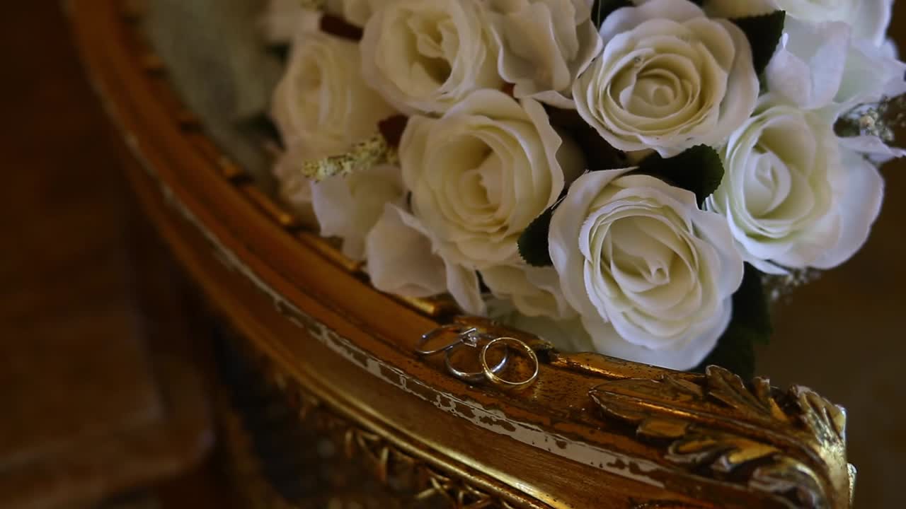 Ramo de rosas blancas nupcial y anillos de boda de los novios