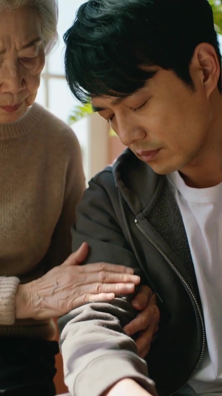 세로 영상: 창가에 기대어 피곤해하는 아들을 보고 팔뚝을 문질러주는 엄마, 스웨터