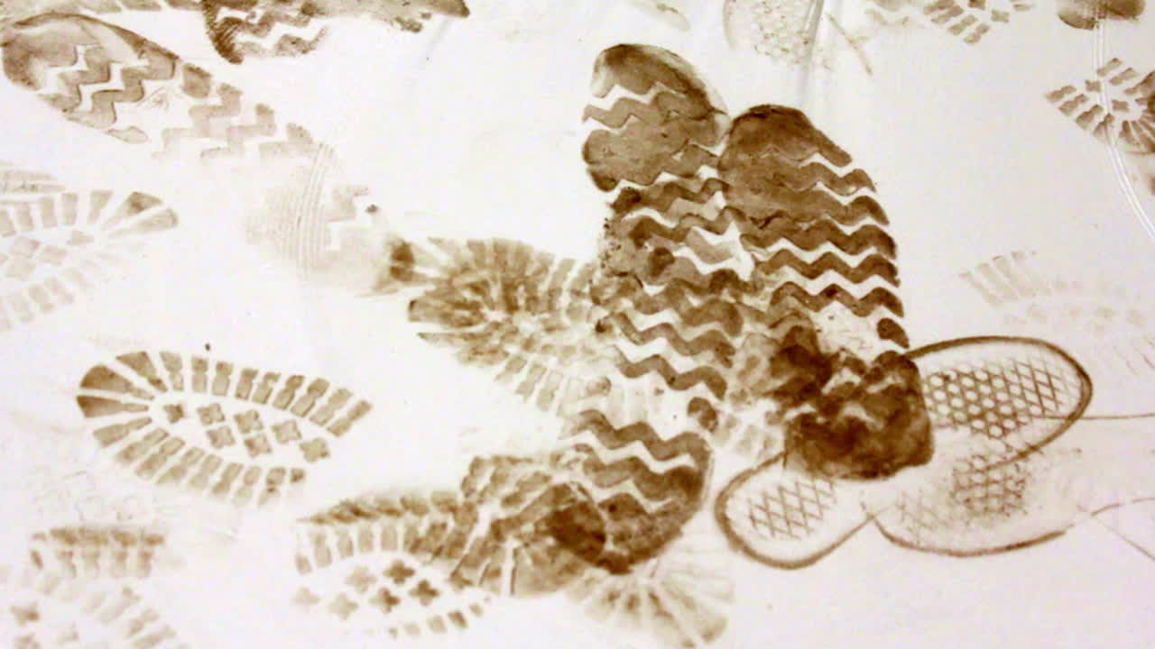 Close-up of dirty boot prints on a white construction floor, showing varied tread patterns left by workers at an active building site