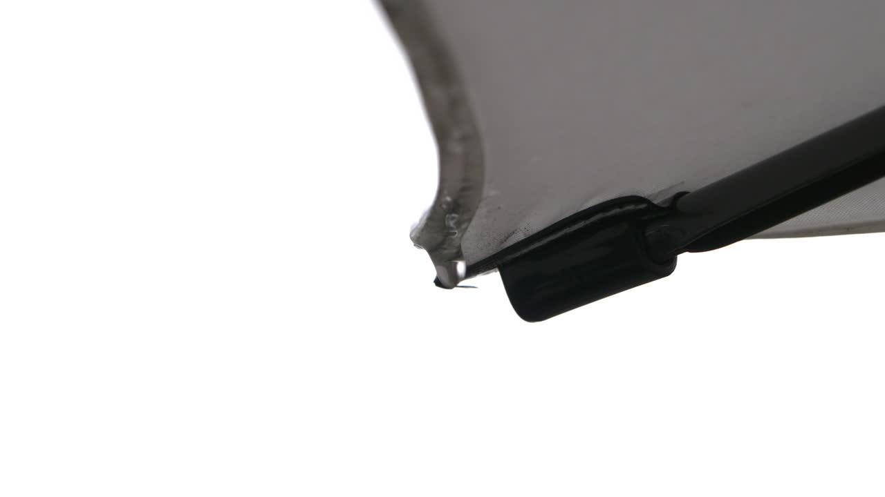 кончик ребра зонтика для патио с капающими каплями дождя на белом фоне