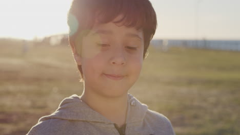 retrato de cerca niño hispano lindo sonriendo feliz mirando tranquilo disfrutando de un día de verano relajado en el parque costero al atardecer infancia despreocupada