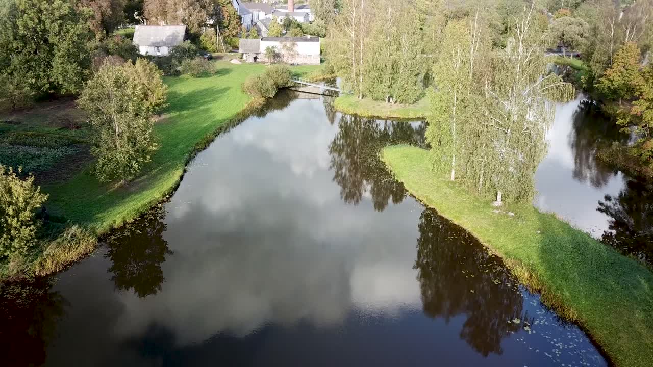 Himmelrefleksion i vanddam i lille landsby i Letland, lavt luftfoto.