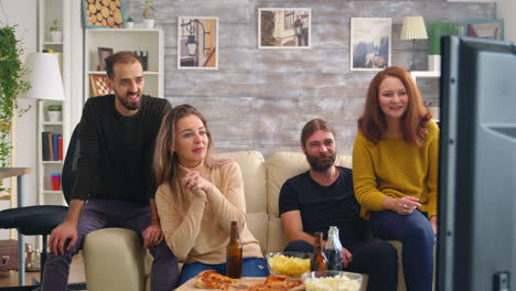 amigos cercanos riendo mientras ven una película en la televisión