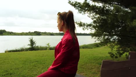 chica sentada, mirando hacia el lago